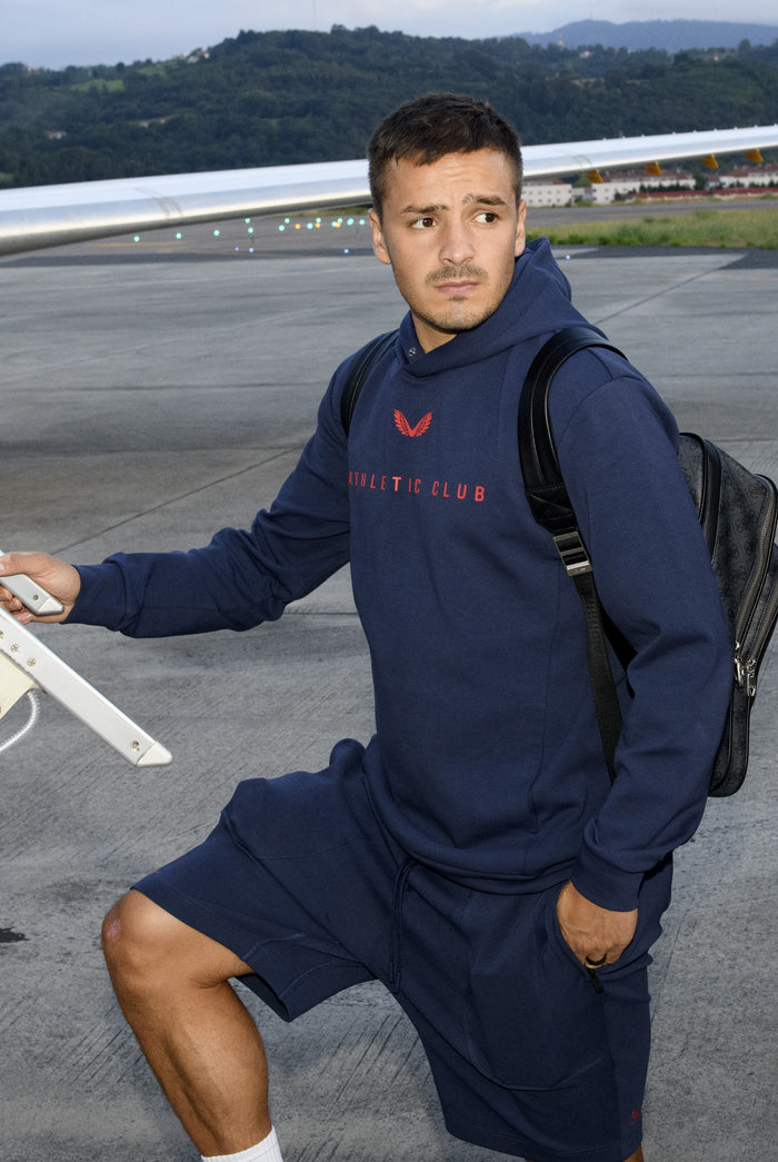 Front view of navy Junior Travel Logo Hoodie with red Athletic Club branding across the chest.