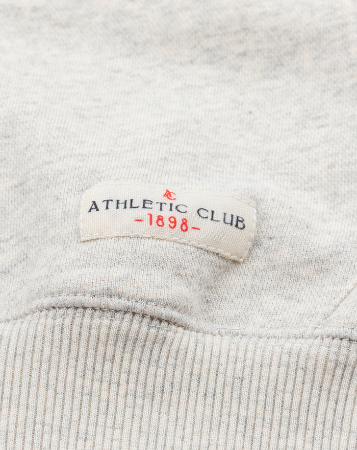 Close-up of the hoodie hem with a stitched label reading ATHLETIC CLUB -1898-