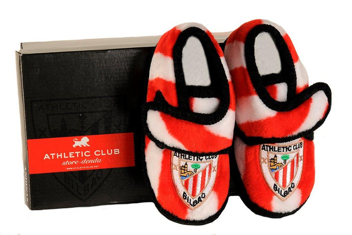 Pair of red and white striped kids slippers with Athletic Club Bilbao crest beside a black box.