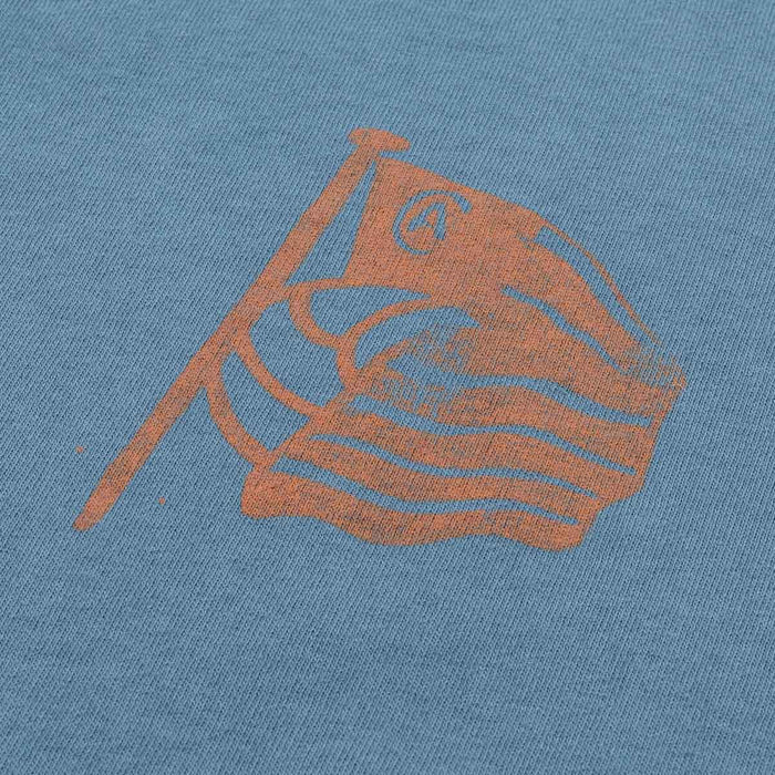 Close up of blue AC Collection Tee fabric with an orange waving flag graphic.