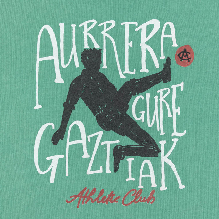 Close-up of the green Junior AC Collection Tee front graphic featuring silhouette and white text