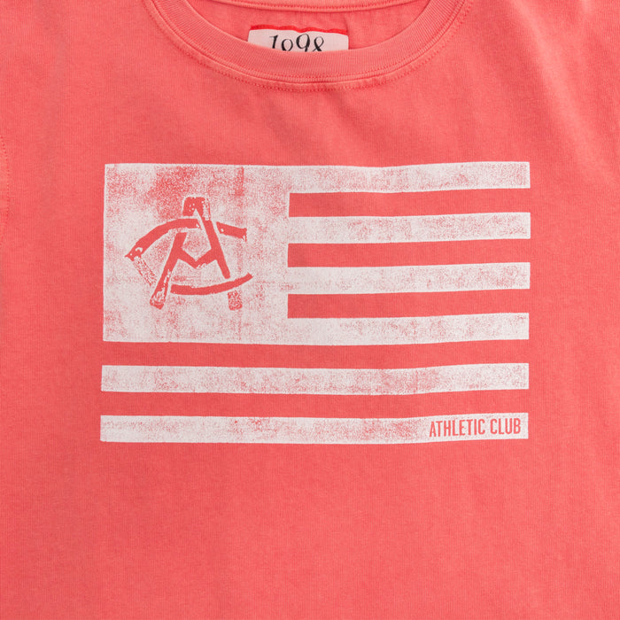 Front close-up of coral pink Junior AC Collection Flag Tee with a distressed white flag graphic