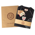 Black junior retro T shirt folded with Athletic Club Bilbao crest and 1898 tag, wrapped in kraft paper packaging.