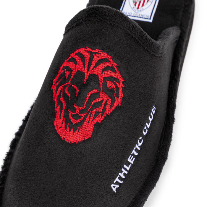 Close up of black slippers featuring a red lion embroidery and white side lettering
