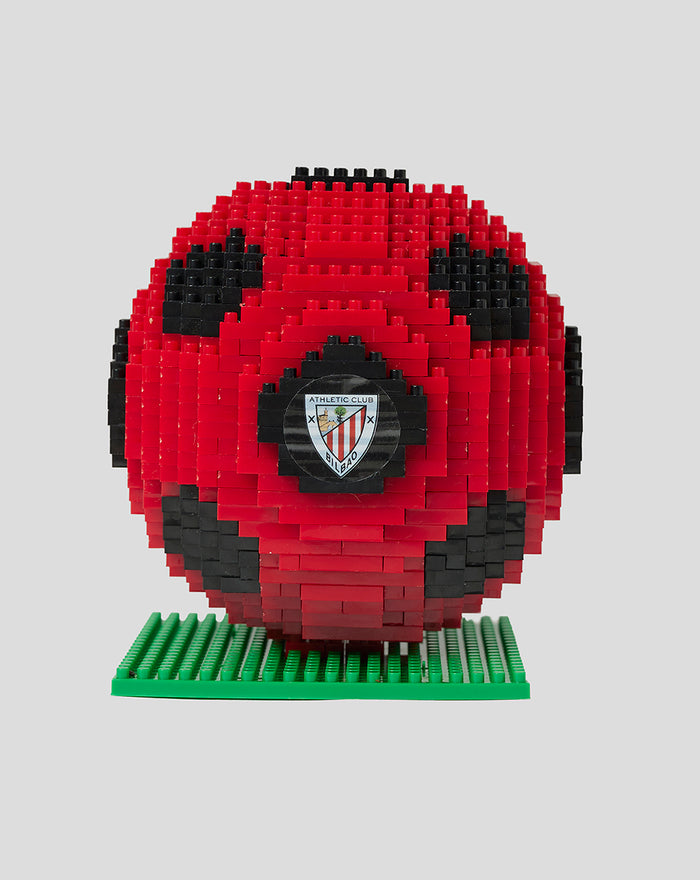 Red and black brick football puzzle sculpture on a green base with a club crest at the center