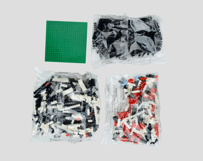 Assorted LEGO bricks in clear bags along with a green base plate ready for assembly.