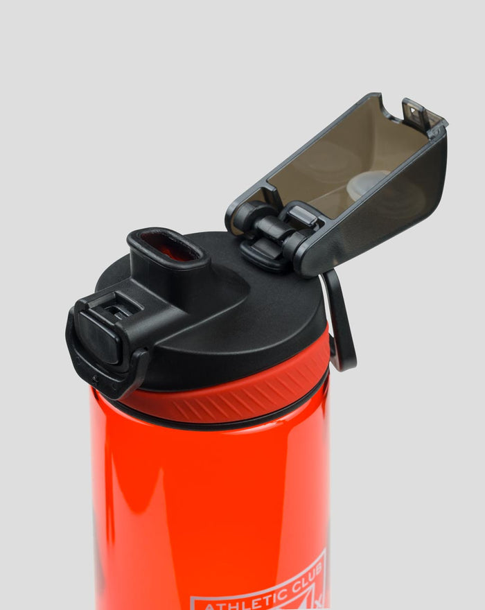Red water bottle with black flip lid open exposing interior and locking mechanism.