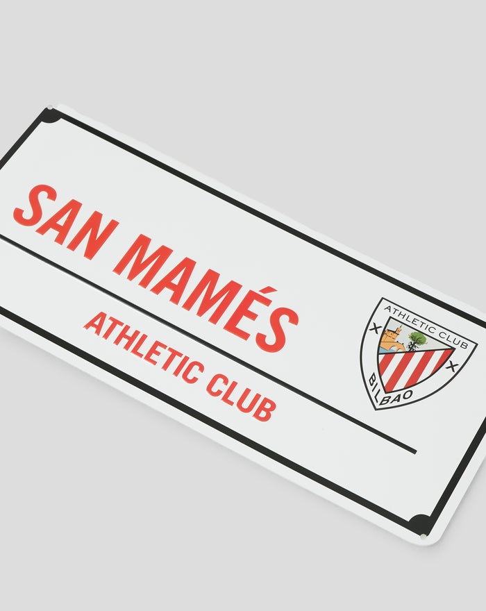 Angled close up of a white sign with red bold text and the Athletic Club Bilbao crest in the lower right corner