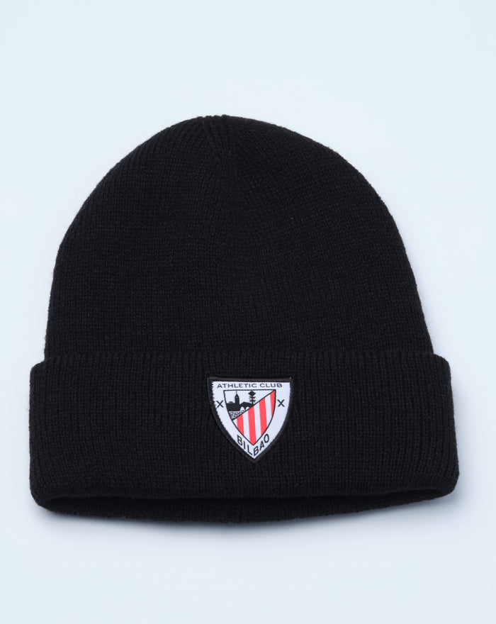 Black beanie with folded cuff and crest patch on the front