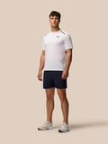 Male model in a white tee and navy Apex Training Shorts standing in a neutral studio.