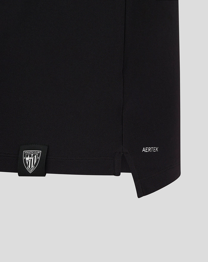 Close up of black CLUB ESSENTIAL SS POLO fabric with a small shield patch at the hem and AERTEK branding