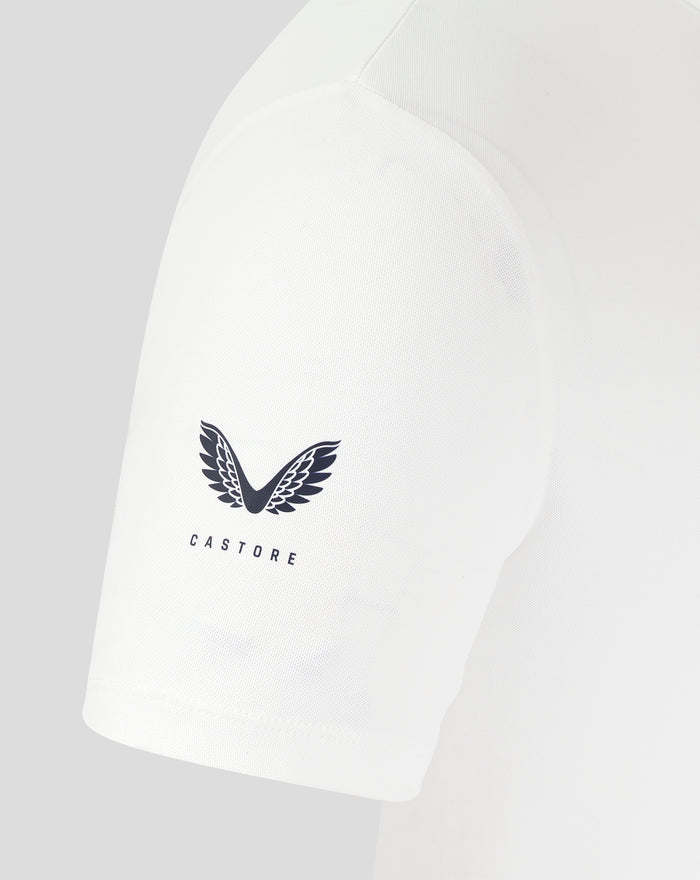 Close-up of white polo front showing crest on the chest and curved shoulder seam