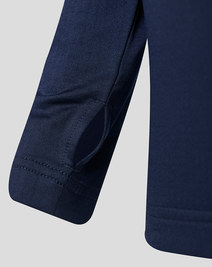 Close-up of navy junior performance midlayer sleeve with curved panel and reinforced stitching.