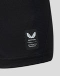 Close up of black jersey fabric showing Castore authentic product patch with white wings