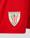 Close up of red junior away shorts fabric with Athletic Club Bilbao crest patch