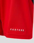 Close-up of the red shorts hem with white CASTORE embroidery on the leg