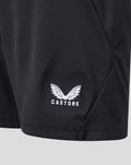Close-up of white Castore logo with wings on black junior goalkeeper shorts.