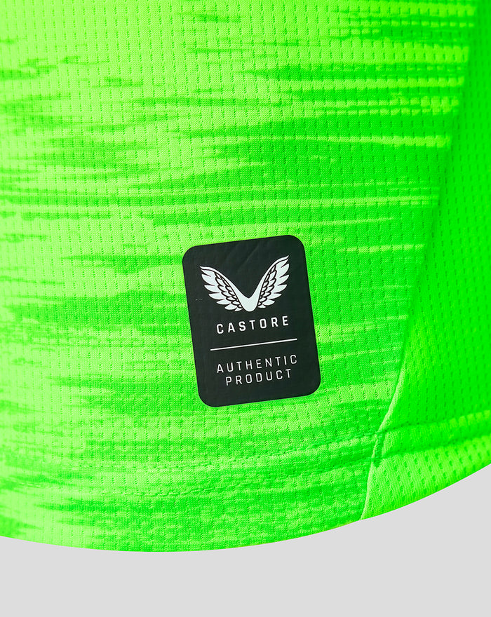 Neon green goalkeeper jersey fabric with a black Castore authentic product patch showing wings