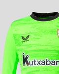 Close up of neon green goalkeeper jersey showing crest on chest and Kutxabank sponsor across the front.