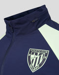 Close up of navy jacket collar with zipper, pale lime panel, and Athletic Club Bilbao crest on the chest.