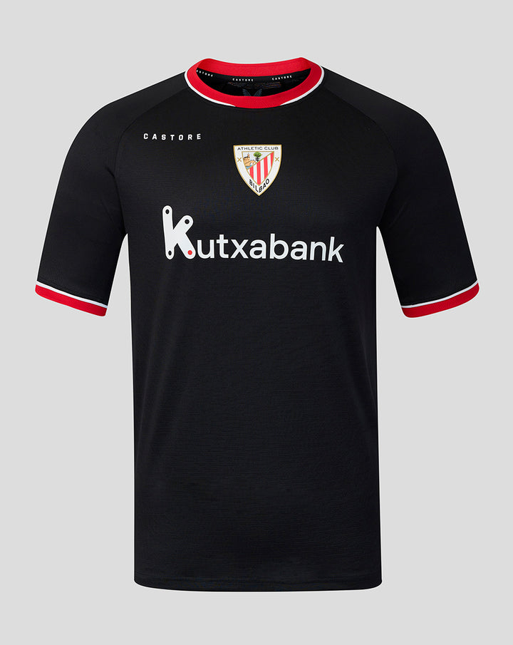 Young male model wearing black away pro short sleeve soccer jersey with red trim and Kutxabank sponsor against gray backdrop