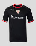 Young male model wearing black away pro short sleeve soccer jersey with red trim and Kutxabank sponsor against gray backdrop