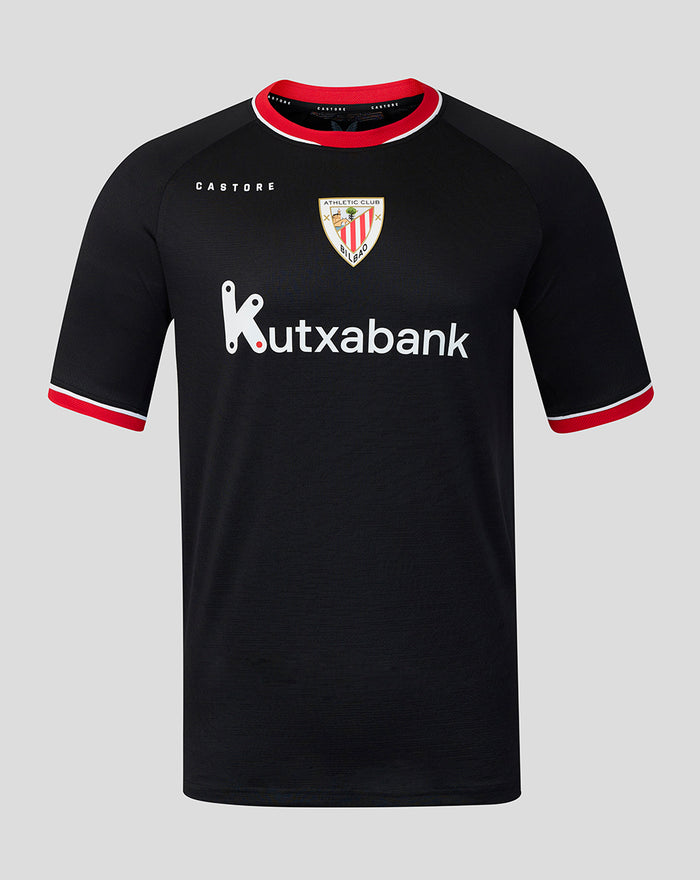 Young male model wearing black away pro short sleeve soccer jersey with red trim and Kutxabank sponsor against gray backdrop