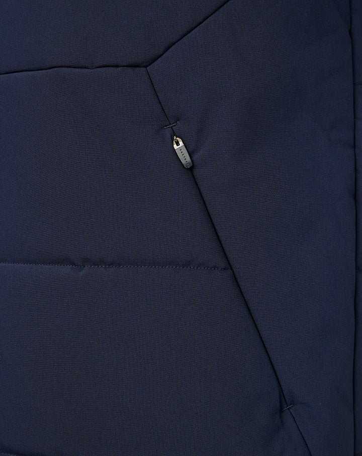 Close-up of navy gilet front zipper and vertical pocket zipper with pull tag.