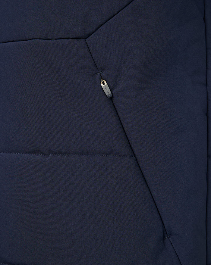 Close-up of navy gilet front zipper and vertical pocket zipper with pull tag.