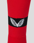 Close up of red Away Change sock for adults with a black band and white winged emblem