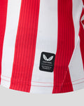 Lower hem area of red and white striped jersey with Castore authentic product badge.