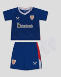 Flat lay of Bilbao away nested baby kit featuring a blue jersey with crest and Kutxabank sponsor, matching shorts and white socks.