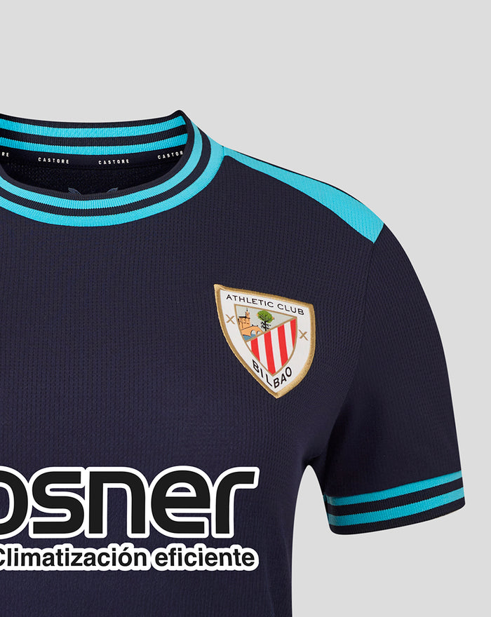 Close-up of navy Kosner Athletic Club away shirt showing turquoise collar and shoulder trim with Castore branding and crest on chest.