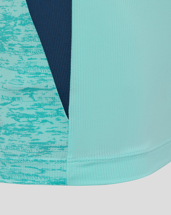 Detail of color-blocked fabric on the tee with turquoise panels, navy insert, and visible stitching.