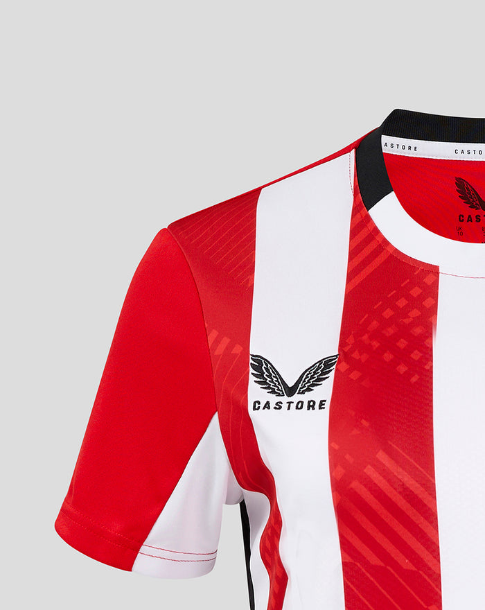 Close up of women's home shirt showing red and white vertical stripes and club crest on the chest