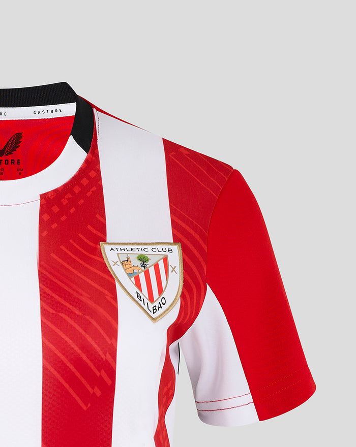 Close-up of the jersey showing left chest club crest on bold red and white stripes and shoulder seam