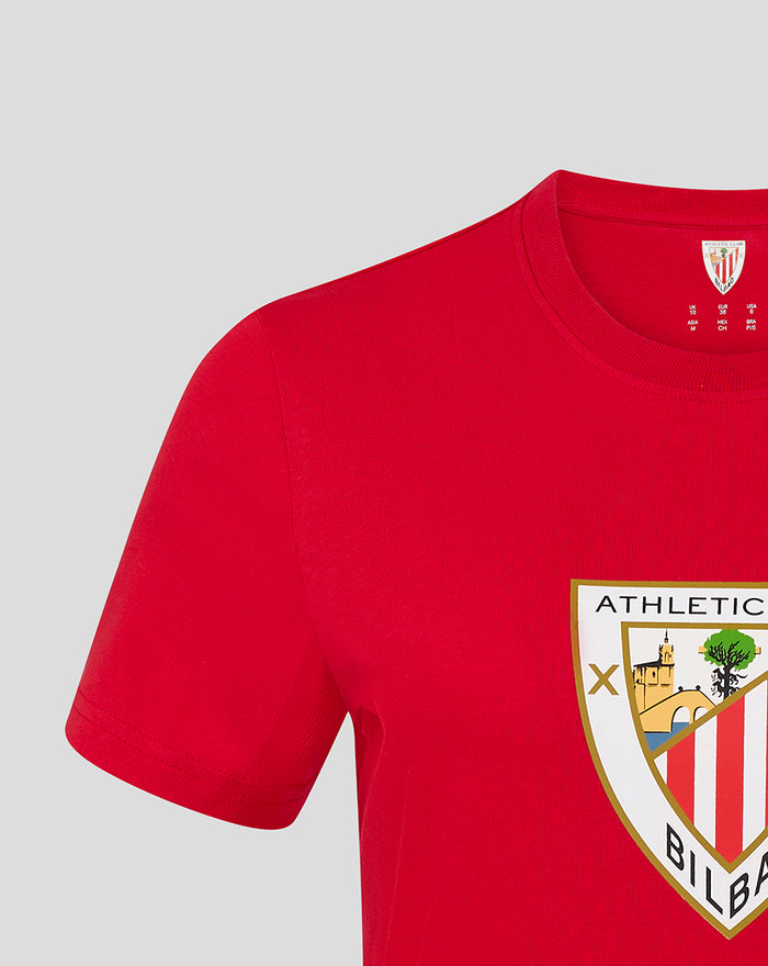 Shoulder and sleeve view of a red crest tee with the shield graphic visible on the chest