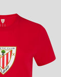 Close up of a red women's core crest tee with a partial shield emblem on the chest