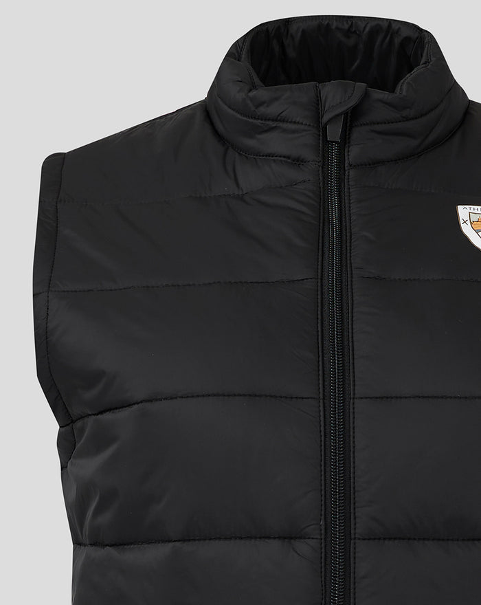 Close up of the black padded gilet with vertical center zipper and crest badge visible on the left chest.