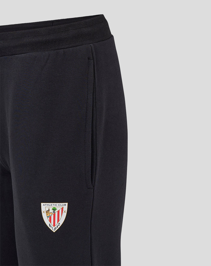 Close-up of black joggers showing the ribbed waistband and crest patch on the leg