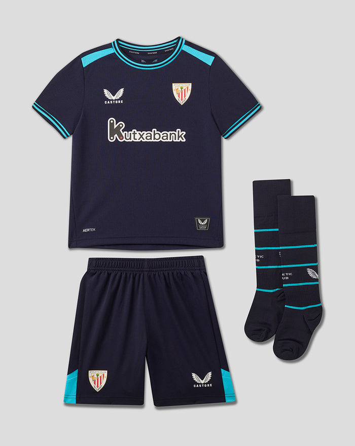 Infant navy Athletic Club away kit laid out showing back of shirt with crest near neck, turquoise trim and side panels, matching shorts with crest and Castore logo, socks