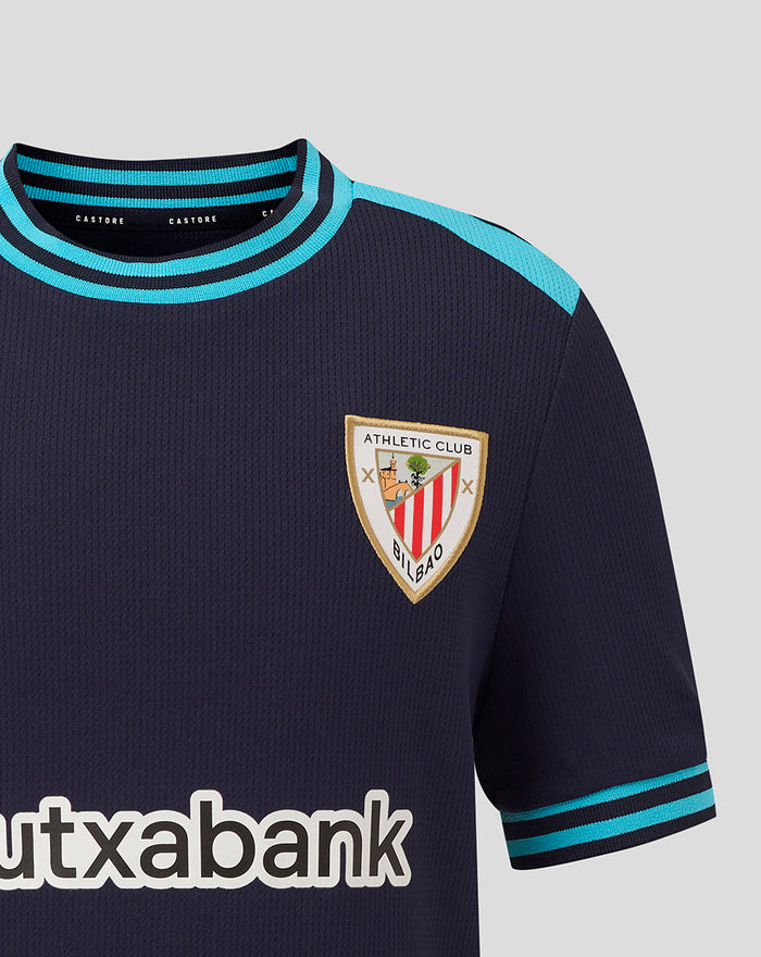 Junior Athletic Club Away shirt close up showing crest on left chest and teal collar trim.