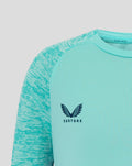 Close-up of aqua junior athletic club tee showing Castore logo on the right chest and Athletic Club crest on the left.