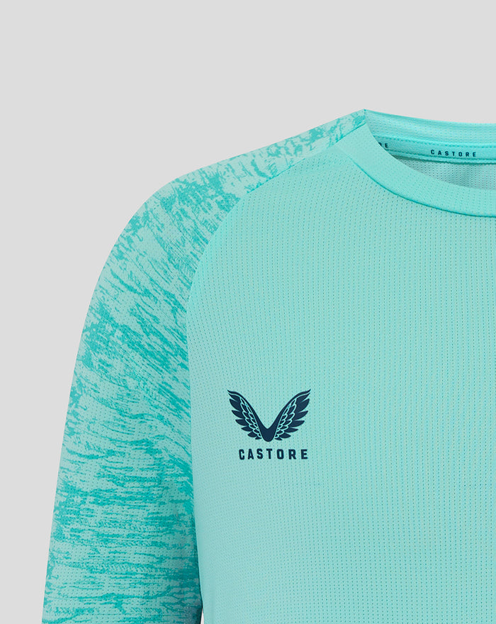 Close-up of aqua junior athletic club tee showing Castore logo on the right chest and Athletic Club crest on the left.