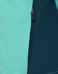 Vertical zipper on turquoise and navy color block panels of the packable shower jacket.