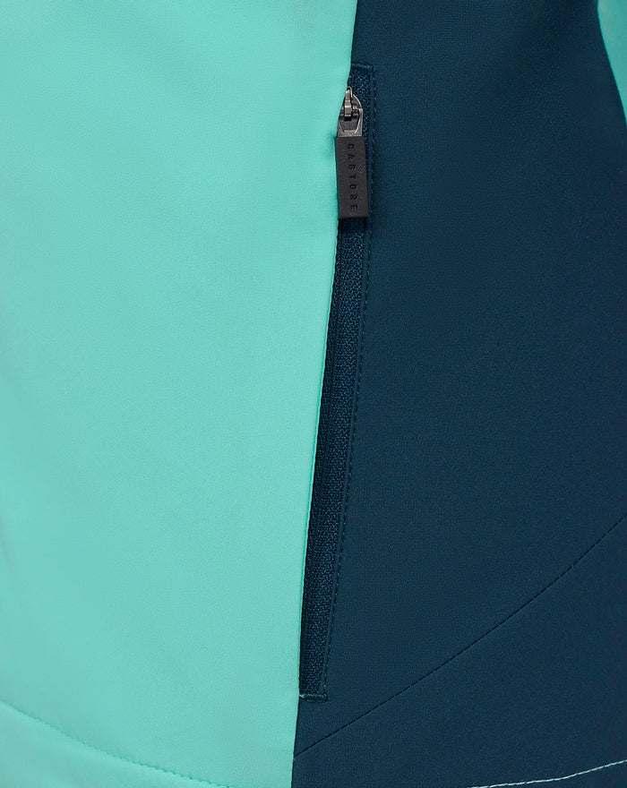 Vertical zipper on turquoise and navy color block panels of the packable shower jacket.