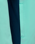 Close up shot of mint green Athletic Club junior hooded jacket showing contrasting navy panel and stitched pocket detail