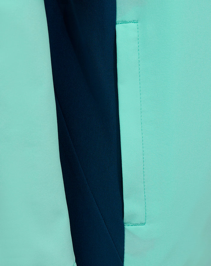 Close up shot of mint green Athletic Club junior hooded jacket showing contrasting navy panel and stitched pocket detail