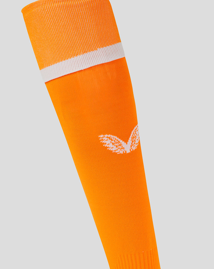 Close-up of bright orange away goalkeeper sock showing a white stripe and Castore logo.