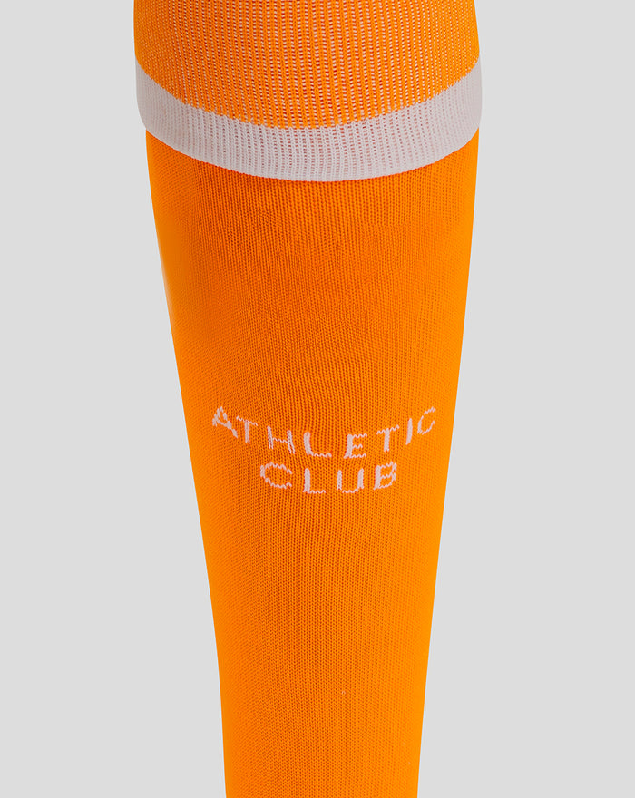 Lower leg close-up of orange Athletic Club goalkeeper sock with white branding text.